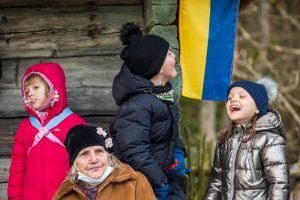 Troje dzieci, w tym dwoje roześmianych, jedna stara kobieta i ukraińska flaga